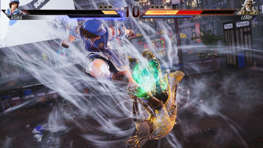 Combat intense entre Asuka et Leroy dans Tekken 8, Asuka exécutant un coup spécial énergétique, illuminant la scène d'éclats lumineux sur un fond urbain.